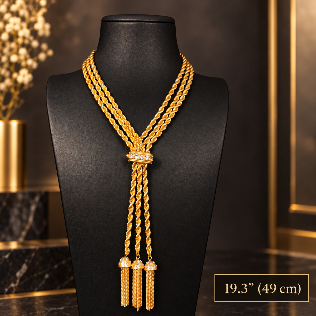 Gold-tone triple rope chain necklace with clear sparkling accents and three chain tassels displayed on a black bust, with a 49 cm length label