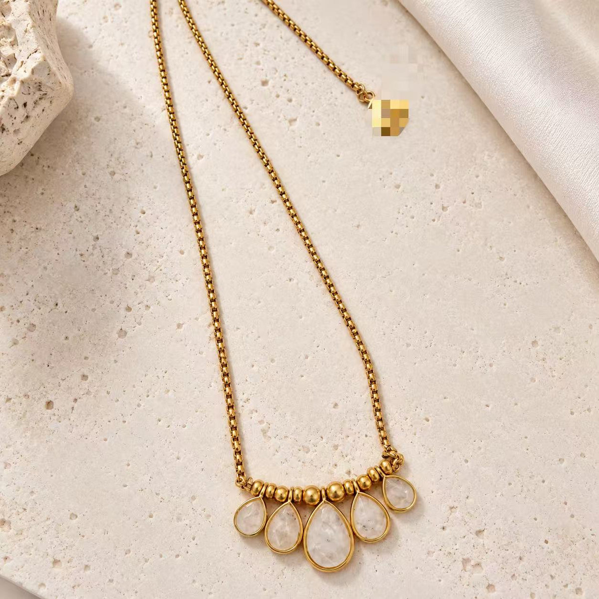 Full-length view of the 24K gold-plated teardrop crystal pendant necklace laid flat