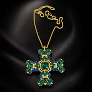 Gold-tone green and blue glass cross brooch pendant necklace on black background