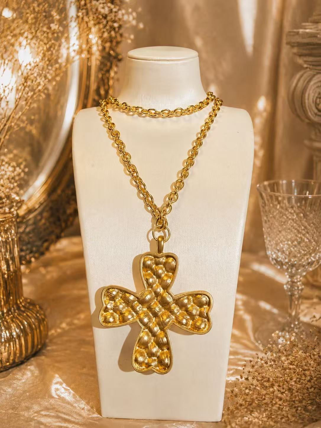Back view showing the textured gold-tone reverse of the cross pendant