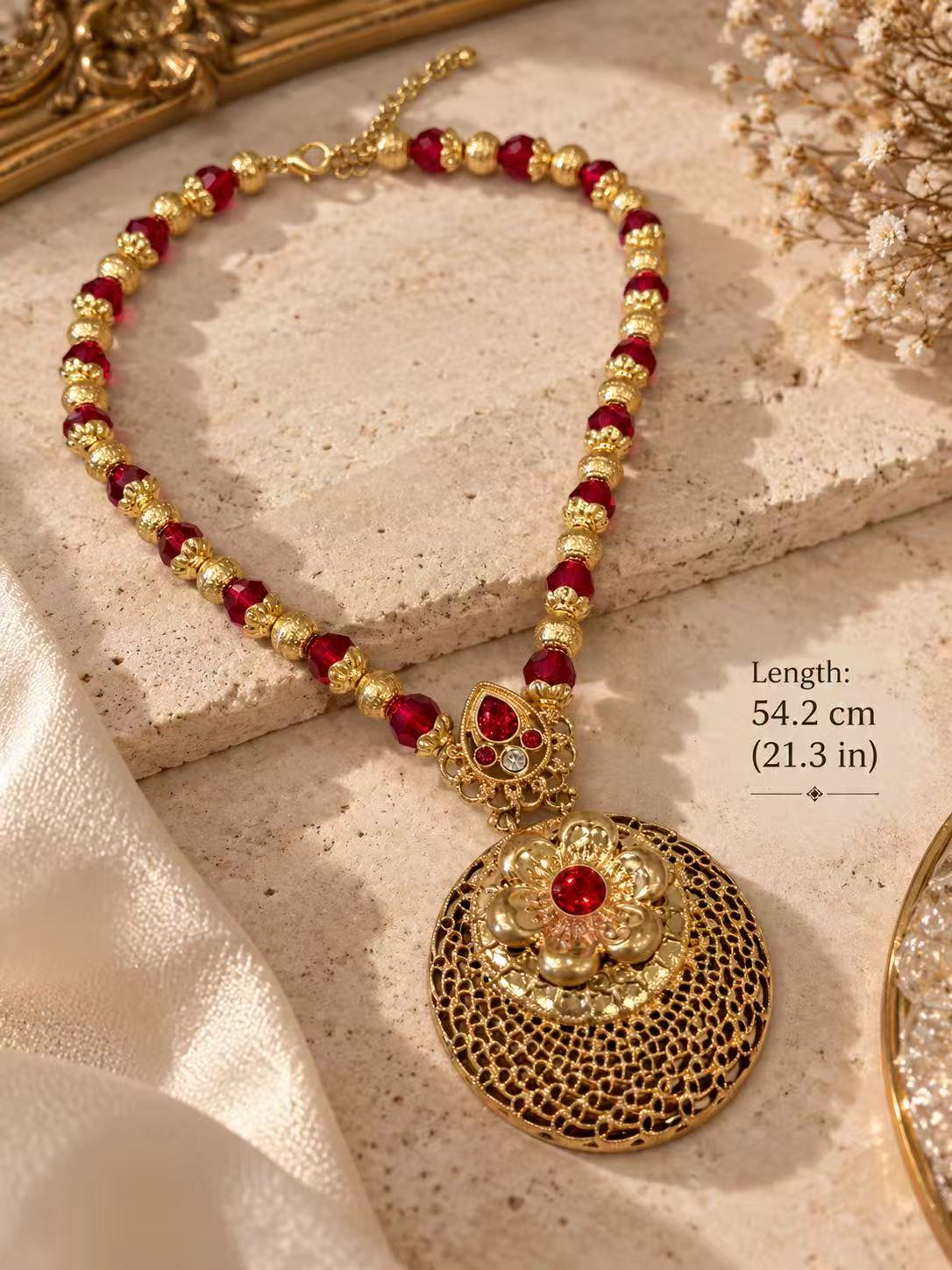 Angled view of the red beaded floral medallion necklace with its lobster clasp and extender chain