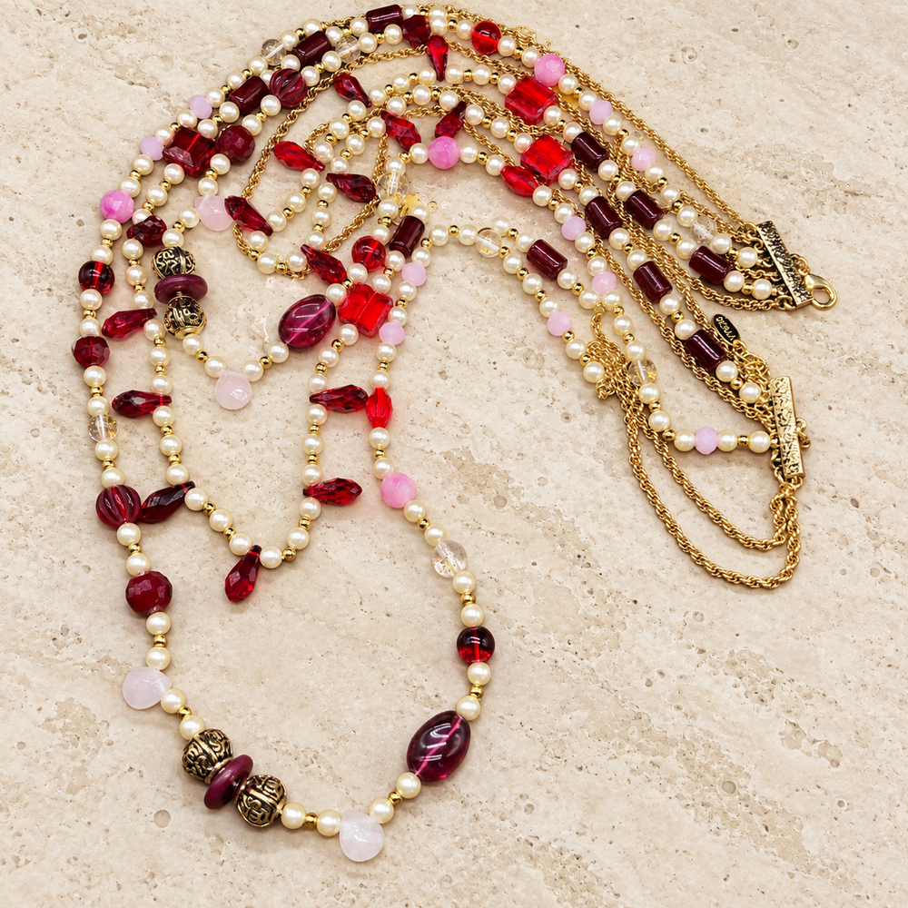 Red crystal and pearl-style multi-strand necklace with gold-tone chains laid flat