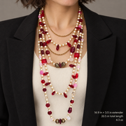 Layered red crystal and pearl-style necklace worn over a cream top with a black jacket