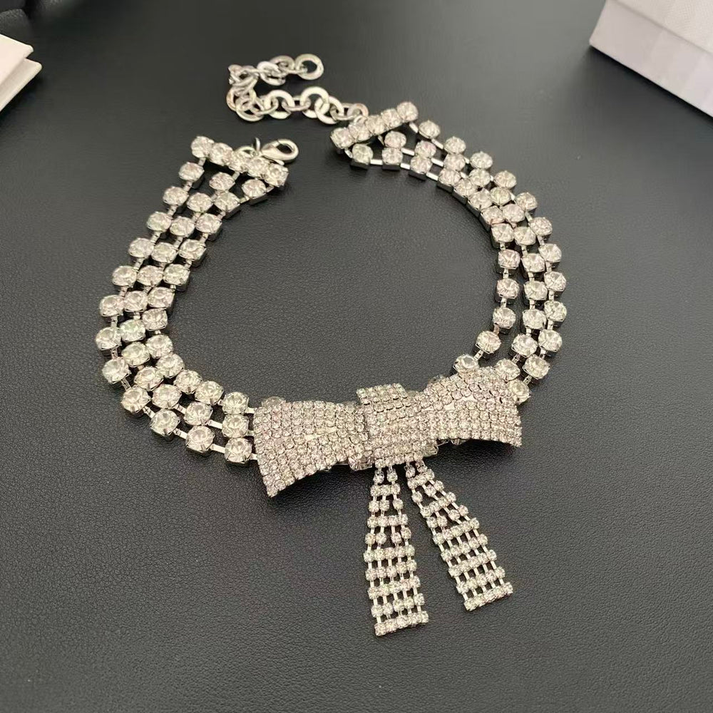 Silver-tone bow choker necklace with three rows of clear faceted stones and dangling bow tails, front view