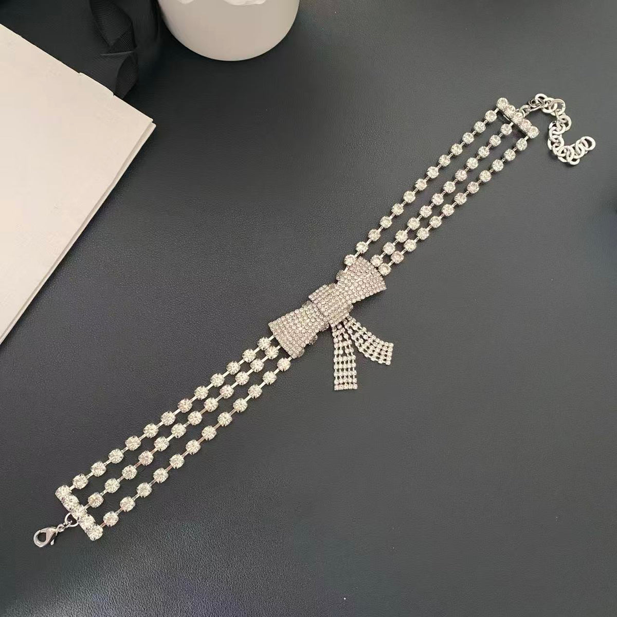 Silver-tone bow choker necklace laid flat showing the three-row design and extender chain