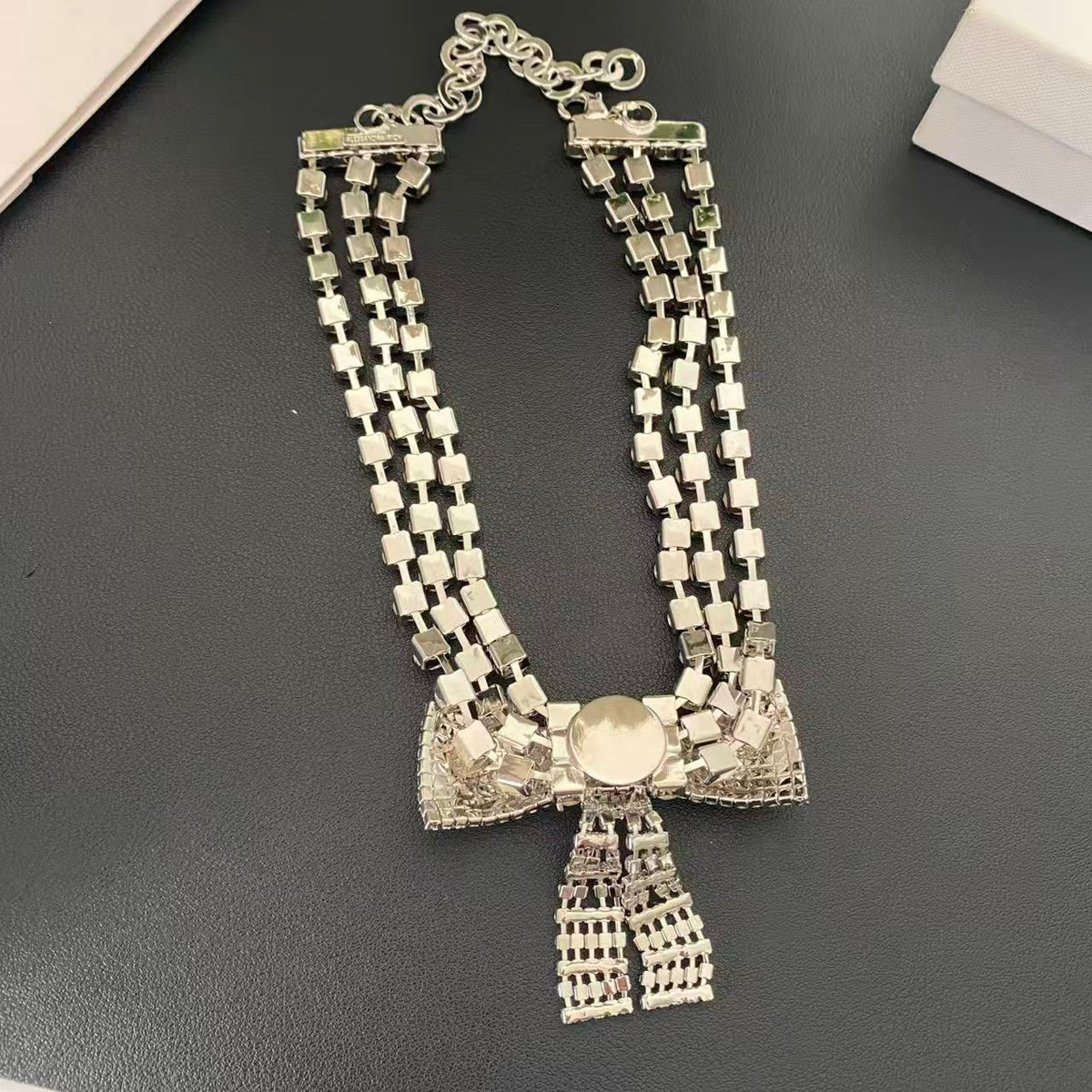 Back view of the silver-tone bow choker necklace showing the clasp and extender chain