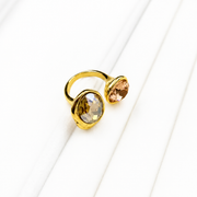 Angled view of an open ring with two warm-toned faceted glass accents on a white background