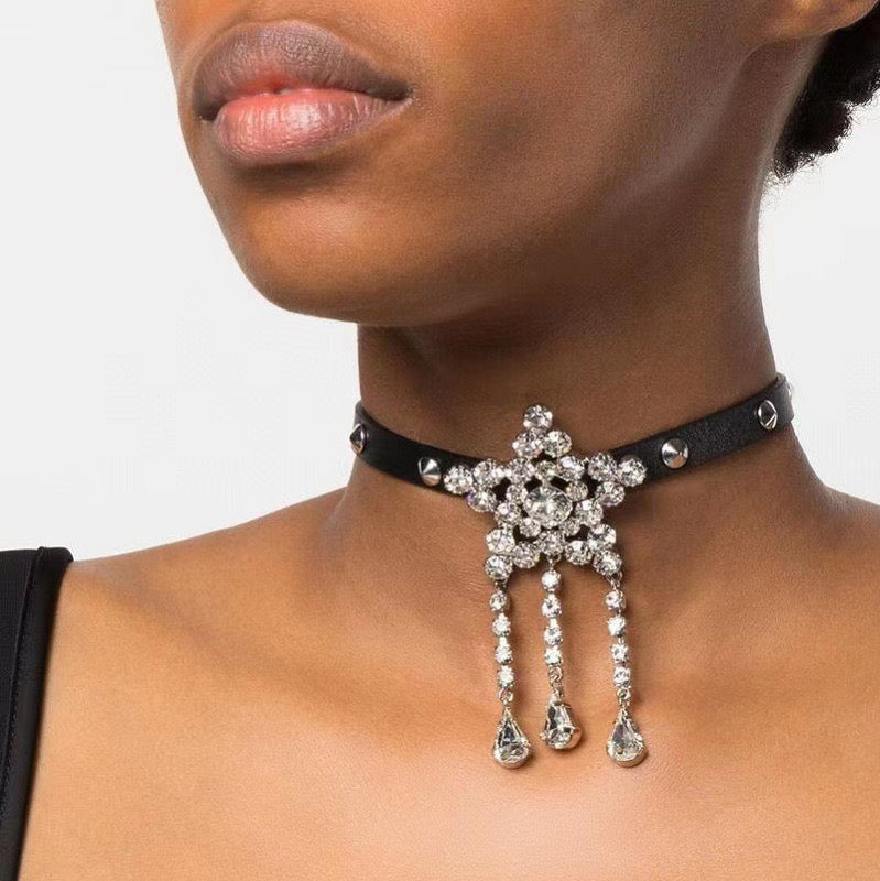 Star tassel choker worn at the neck, showing the black band, silver-tone studs and three teardrop drops