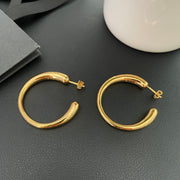 Pair of gold-plated brass hoop earrings on a dark display surface
