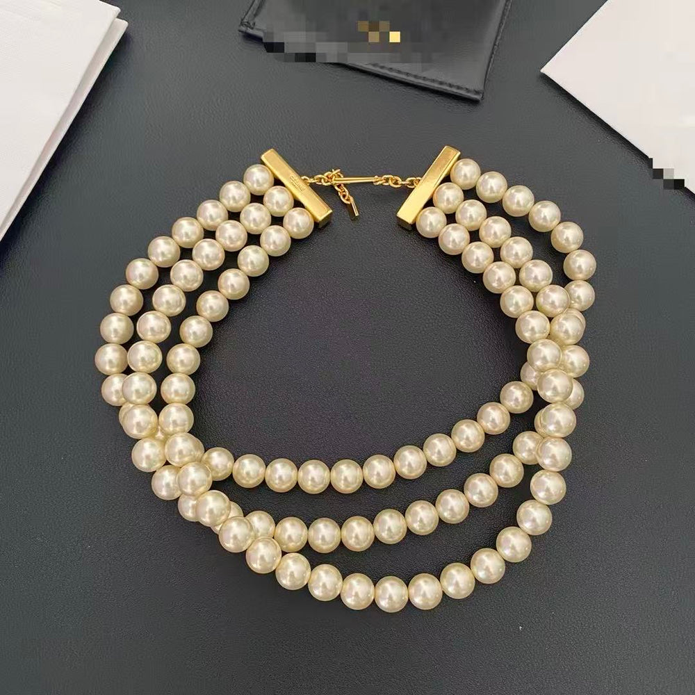Three-strand ivory pearl-style choker necklace with gold-tone end bars and hook fastening