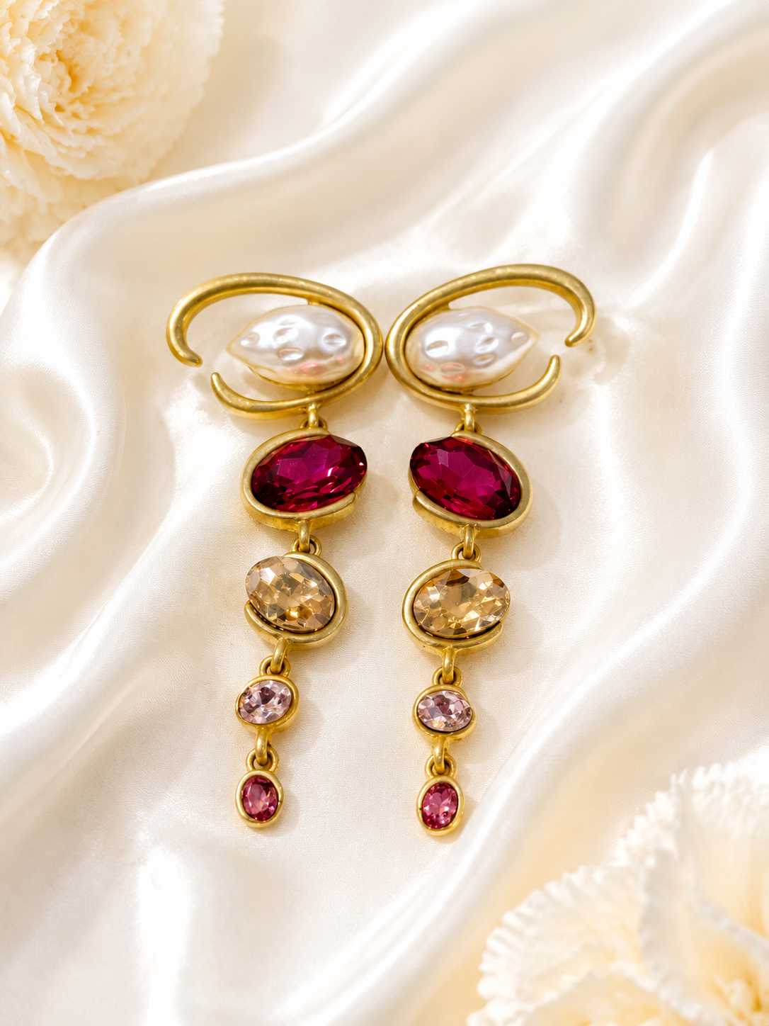 Baroque-inspired magenta rhinestone-style earrings on cream satin