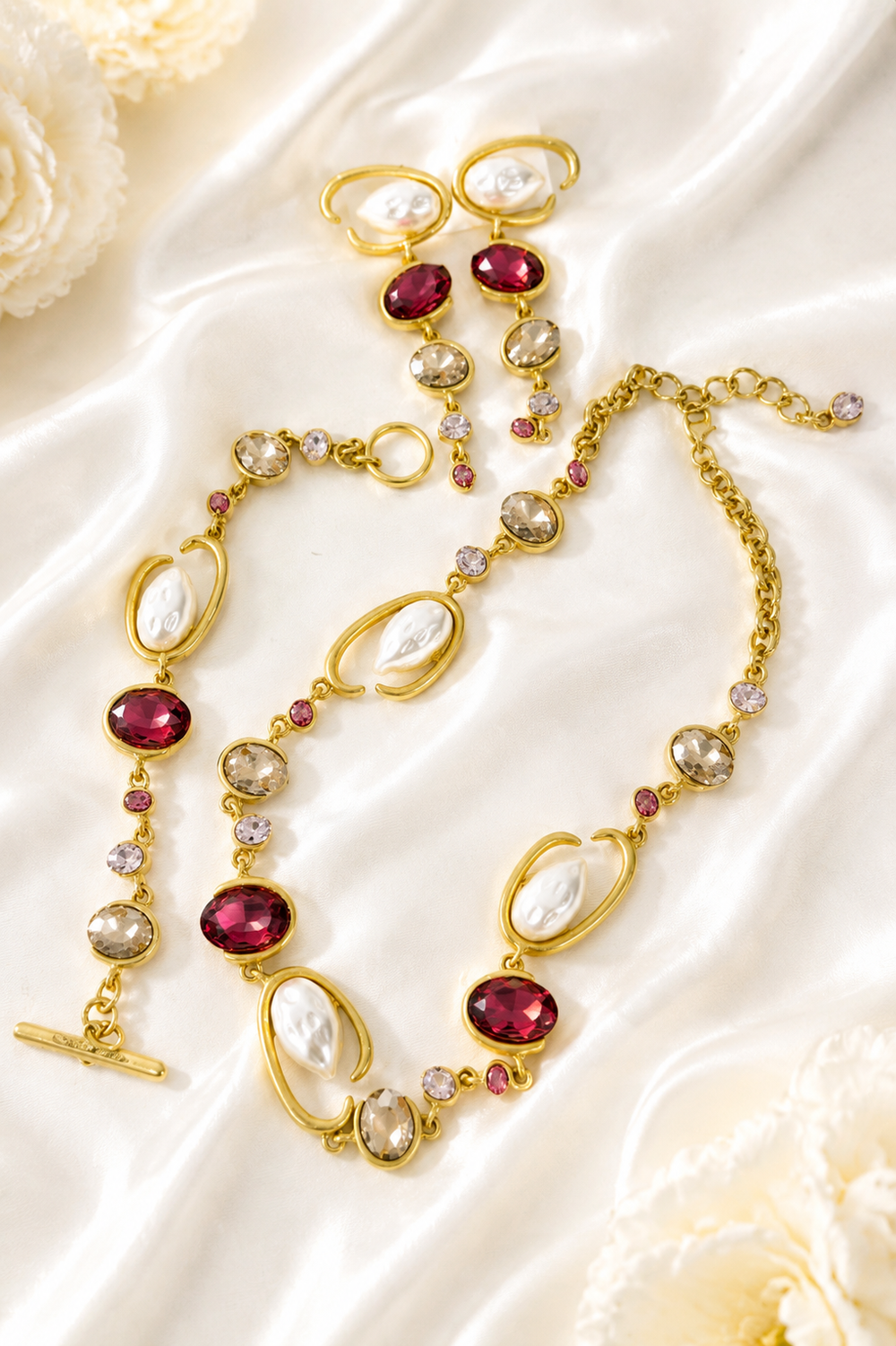 Baroque-inspired magenta rhinestone-style jewelry set on cream satin