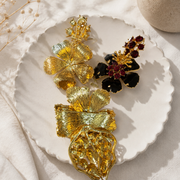 Black enamel-style ruby-red crystal-style brooch set detail view on white dish