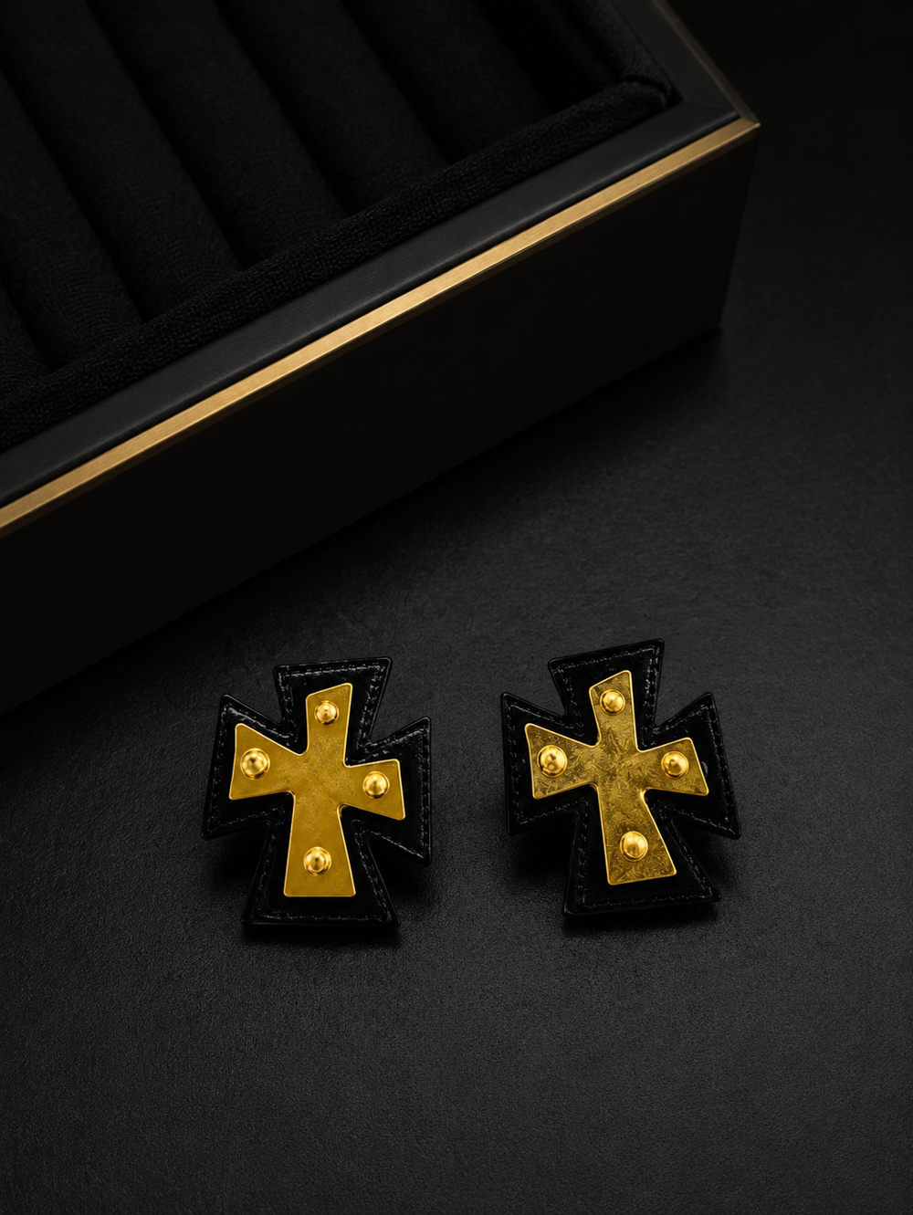 Front view of black leather cross statement earrings with gold-tone accents