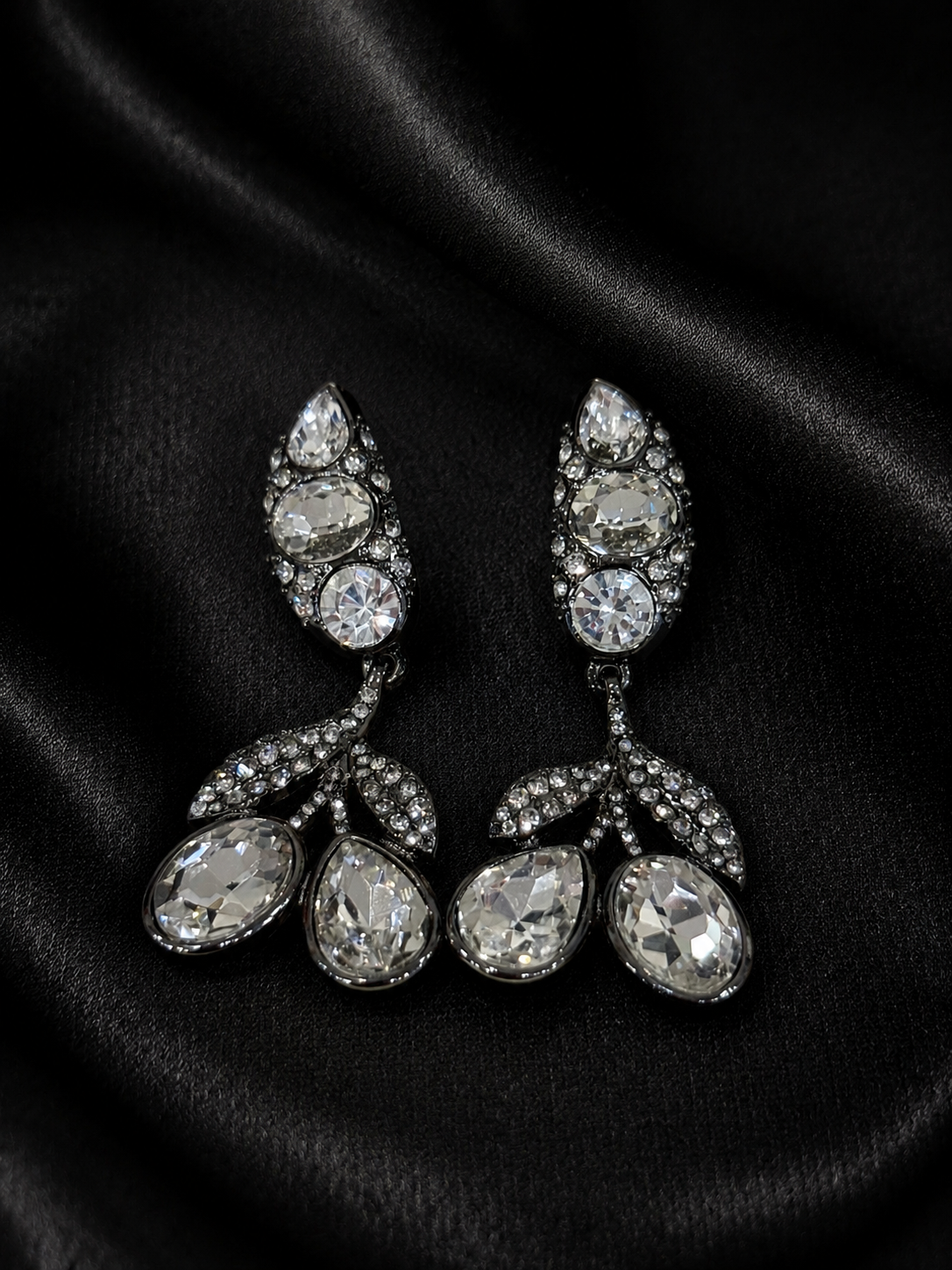 Clear crystal-style drop earrings with faceted accents on black background