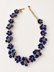Deep blue enamel floral necklace on ivory fabric