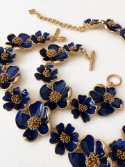 Deep blue enamel floral necklace and bracelet close-up on ivory fabric