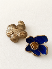 Deep blue enamel floral stud earring shown from front and back on ivory fabric