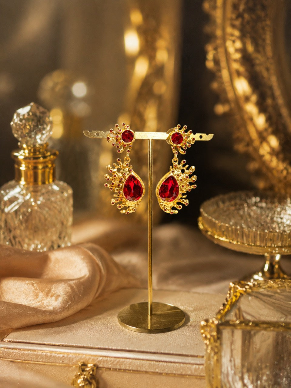 Gold-tone Barbie pink red crystal-style teardrop stud earrings on display stand