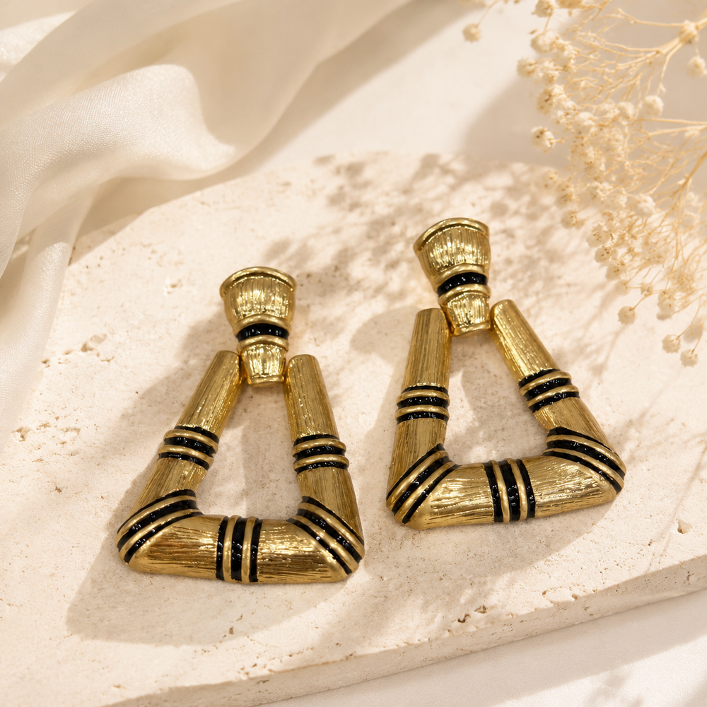 Pair of gold-tone triangle stud earrings with black enamel-style stripe accents, front view