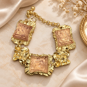Gold-tone statement bracelet with pink textured rectangular centers and sculpted links.