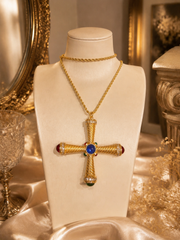 Gold-tone cross pendant necklace with blue red and green cabochon-style accents on display bust