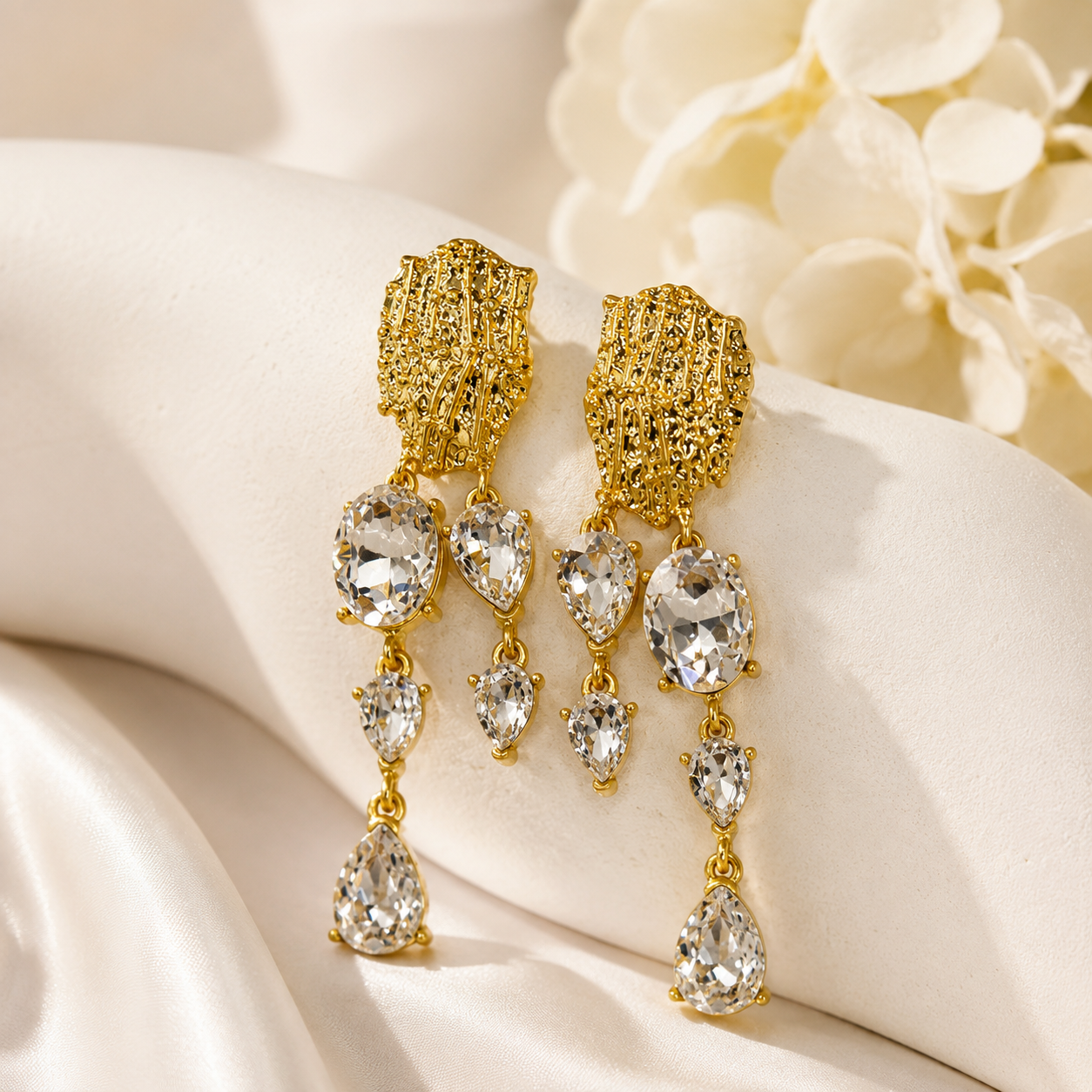 Clear crystal-style teardrop tassel earrings with gold-tone textured tops