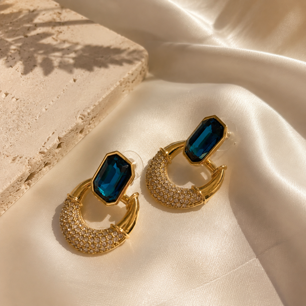 Gold-tone faceted glass crescent stud earrings in teal blue front view