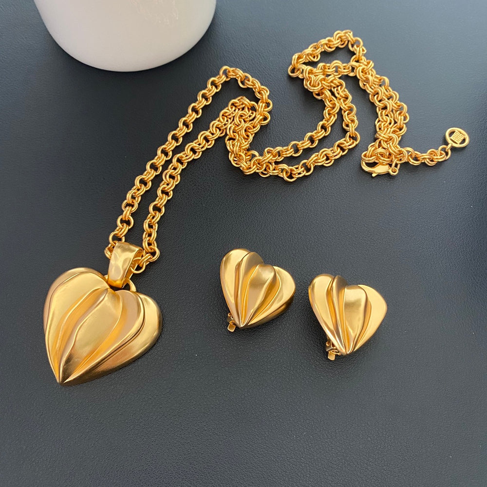 Gold-tone folded heart clip-on earrings and necklace set on dark background