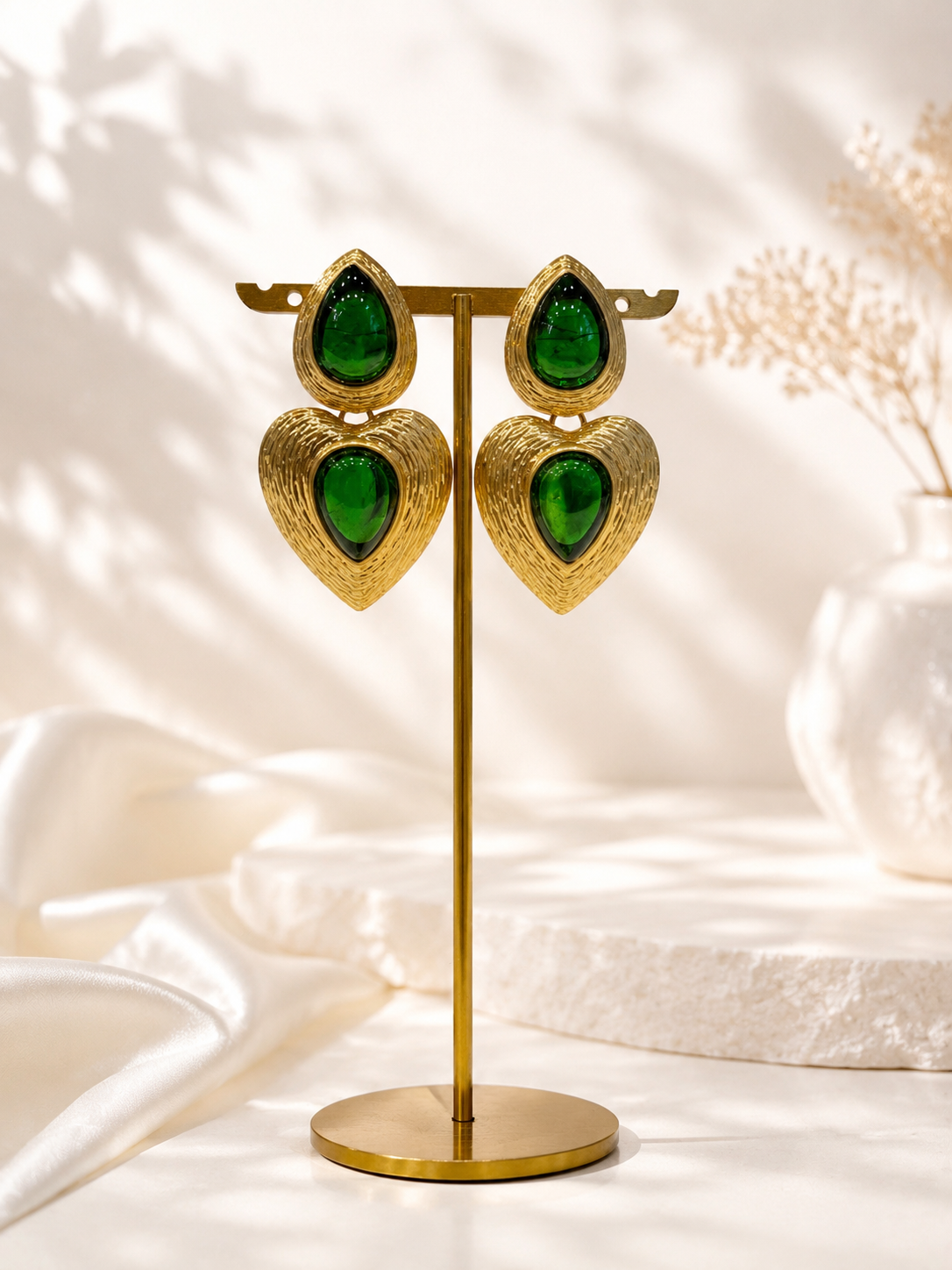 Green gold-tone glass heart drop stud earrings on display