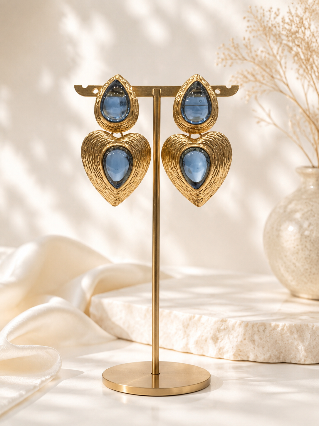 Light blue gold-tone glass heart drop stud earrings on display