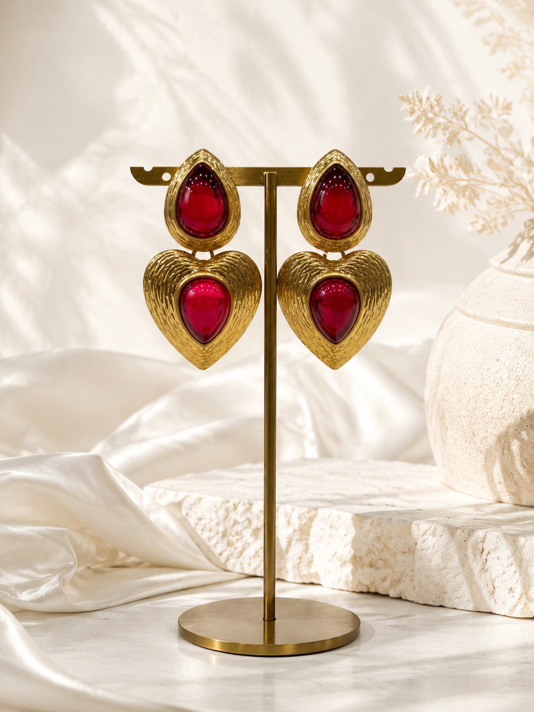 Red gold-tone glass heart drop stud earrings on display