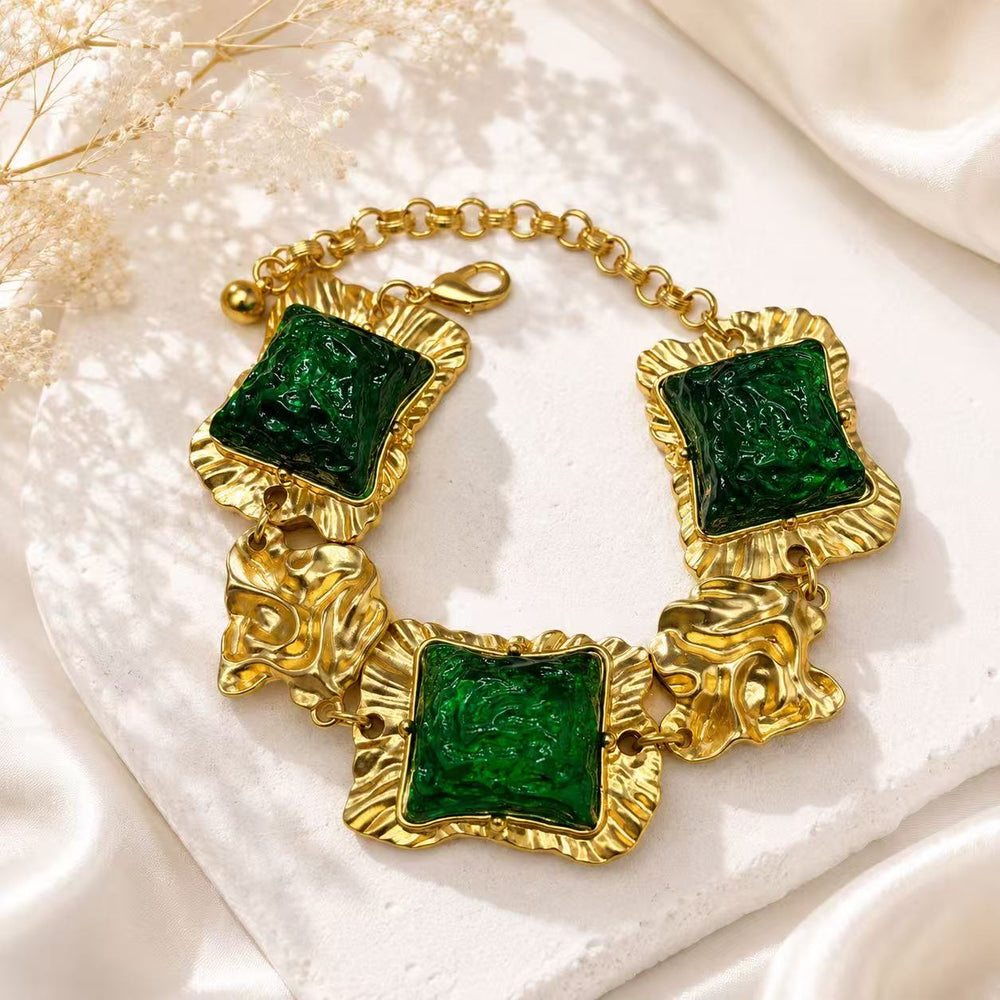 Gold-tone statement bracelet with green glass-style square accents and textured links