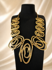 Gold-tone hammered swirl statement necklace front display on black bust