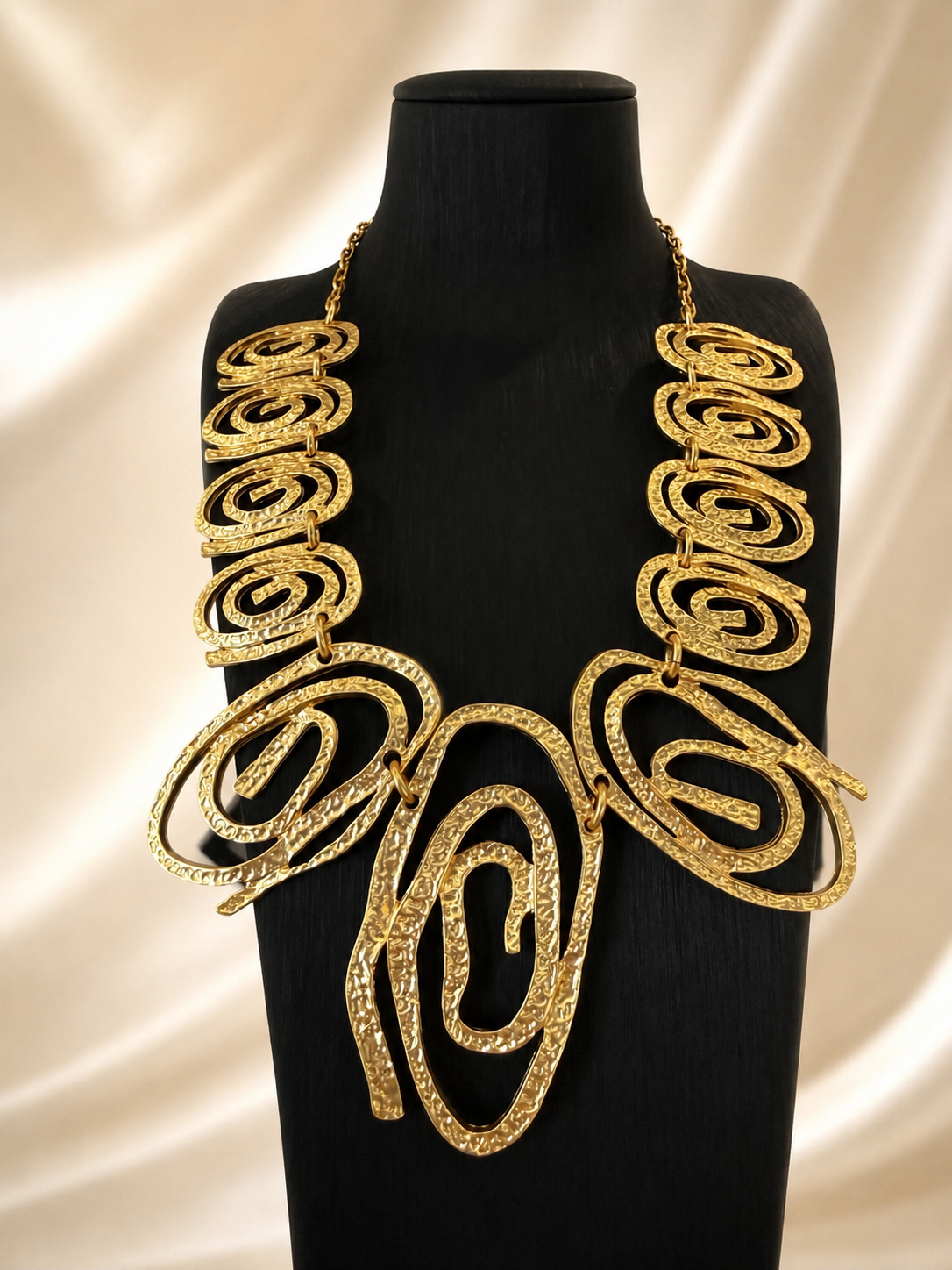 Gold-tone hammered swirl statement necklace front display on black bust