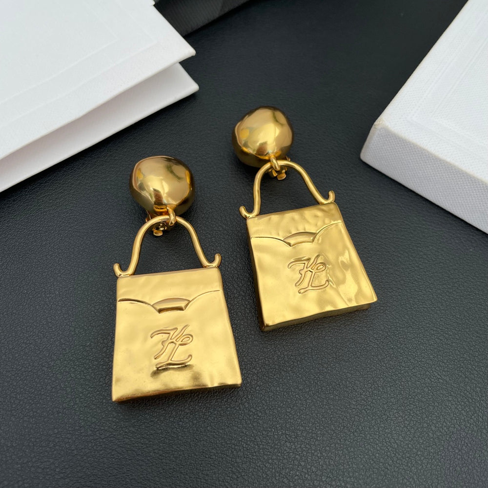 Front view of gold-tone handbag-shaped drop clip-on earrings with domed tops and a script-style motif