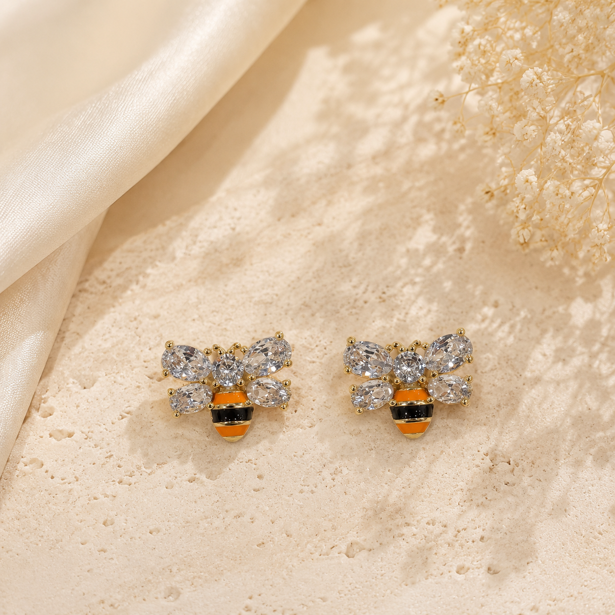 Pair of gold-tone mini bee crystal-style stud earrings with clear crystal-style wings and yellow and black stripe details