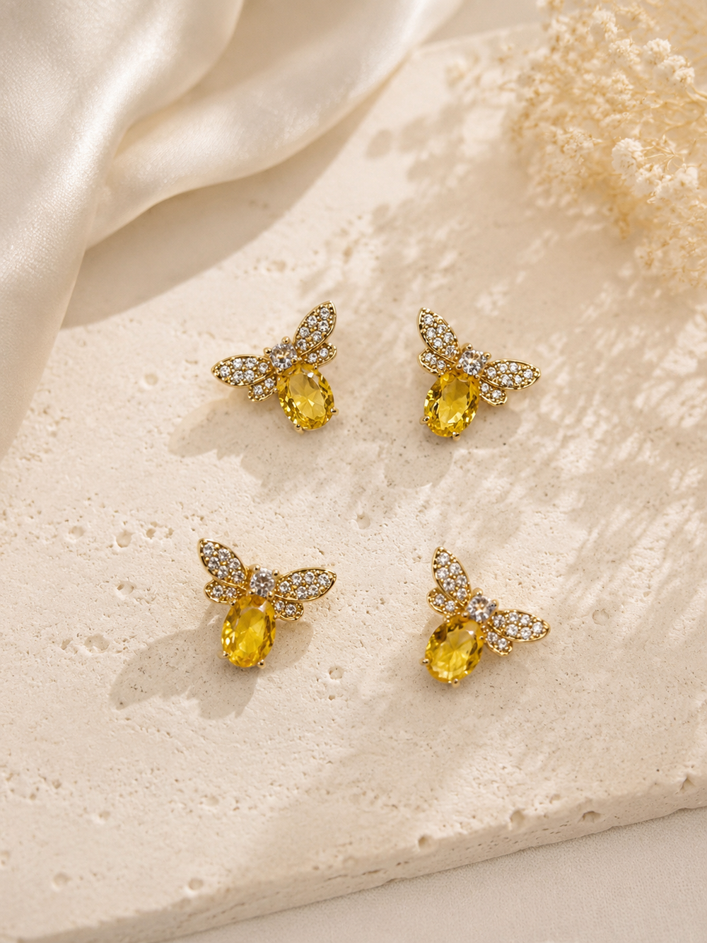 Gold-tone mini bee stud earrings with yellow stone-style bodies and clear crystal-style wings, multiple pairs shown