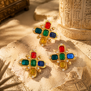 Gold-tone multicolor crystal-style brooch and stud earrings set styled on warm stone background