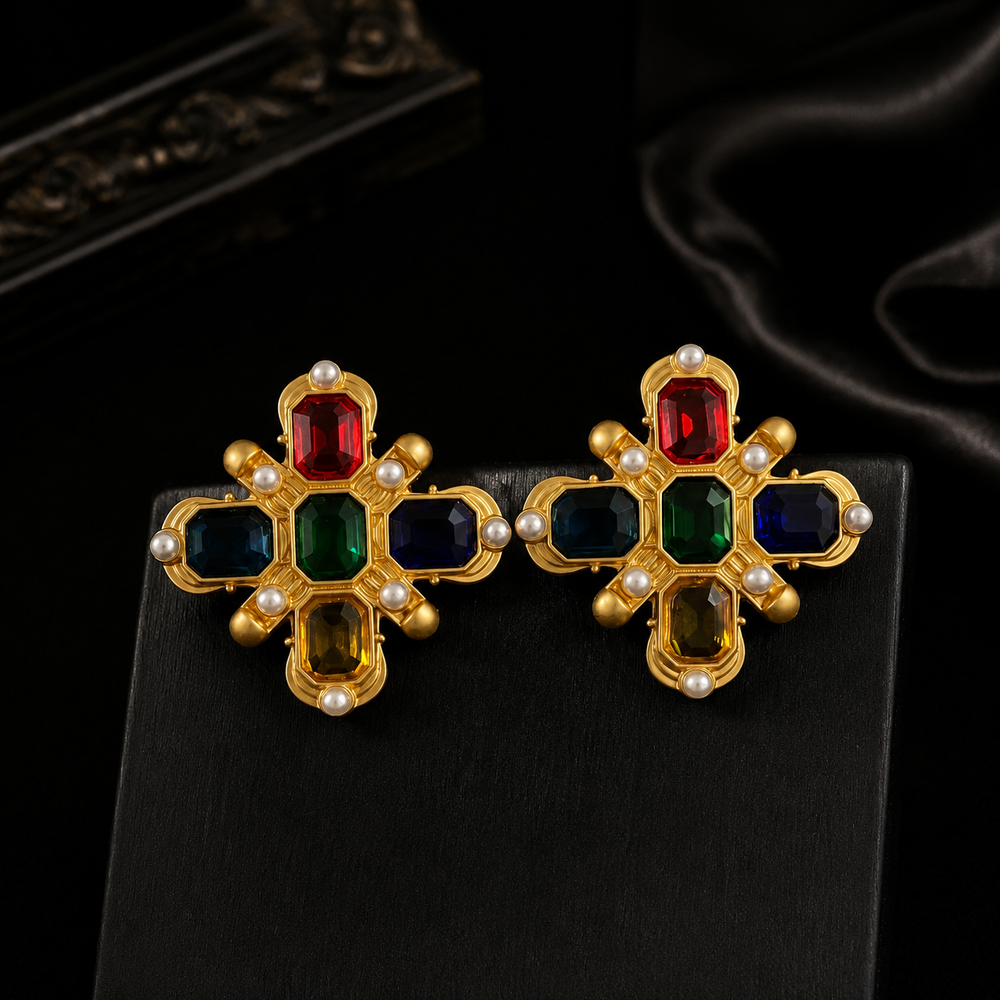 Gold-tone multicolor crystal-style stud earrings with pearl-style accents on black display