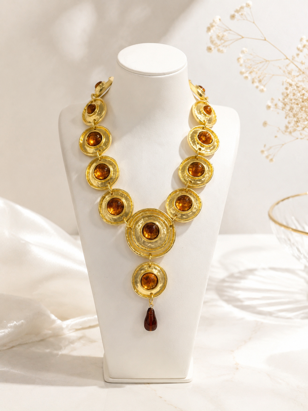 Gold-tone statement necklace with orange stone-style accents on a jewelry display