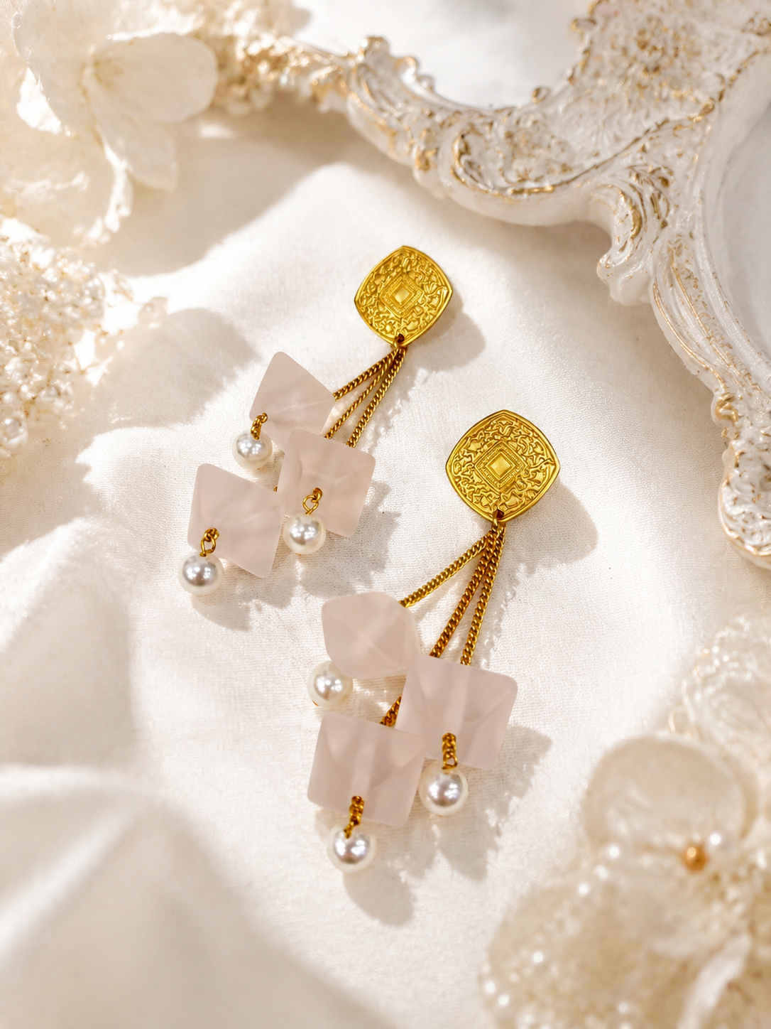Gold-tone petal drop stud earrings with cascading chains and pearl-style beads, detail view
