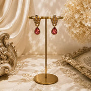 Gold-tone pink teardrop crystal-style stud earrings front view
