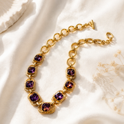 Gold-tone chain necklace with purple crystal-style accents angled view