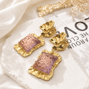 Gold-tone statement stud earrings with purple glass-style square accents and sculptural tops