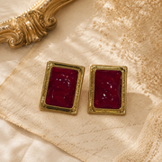 Gold-tone rectangular red glass-style stud earrings front view