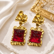 Gold-tone statement stud earrings with red glass-style square accents and sculptural tops