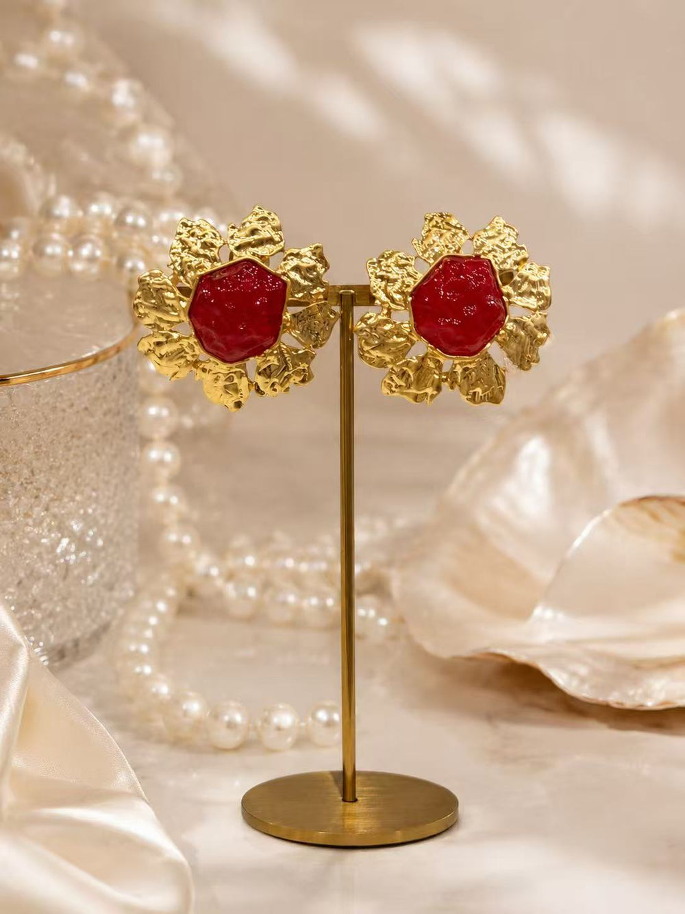 Gold-tone red glass sunflower clip-on earrings on display stand