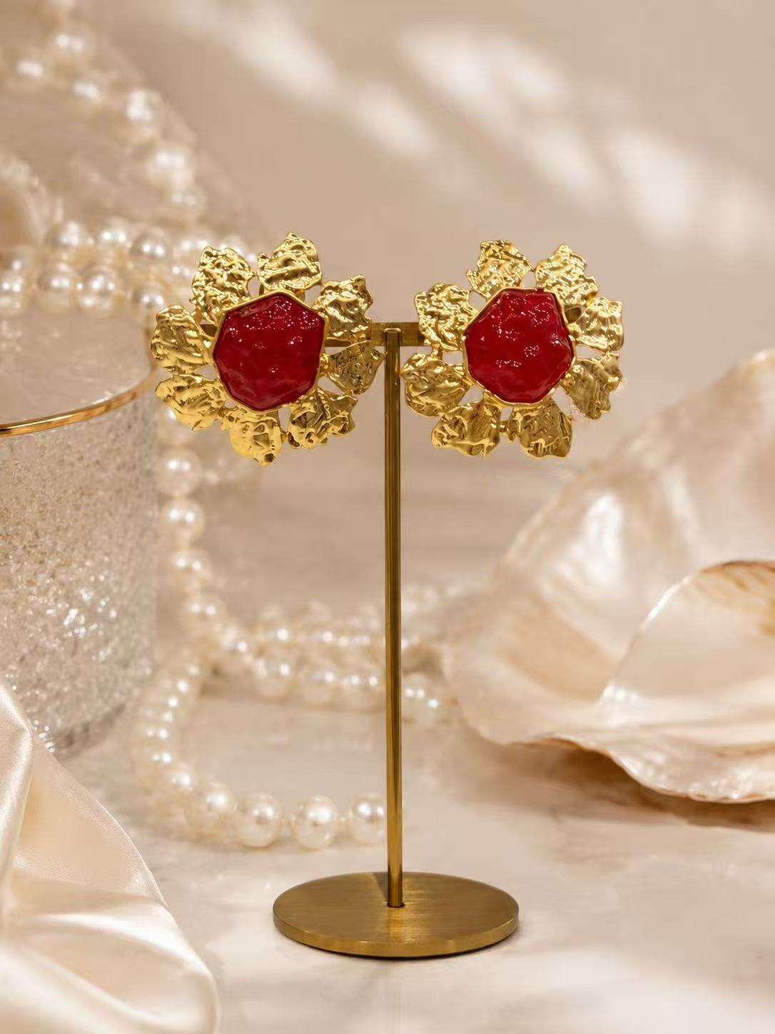 Gold-tone red glass sunflower clip-on earrings on display stand