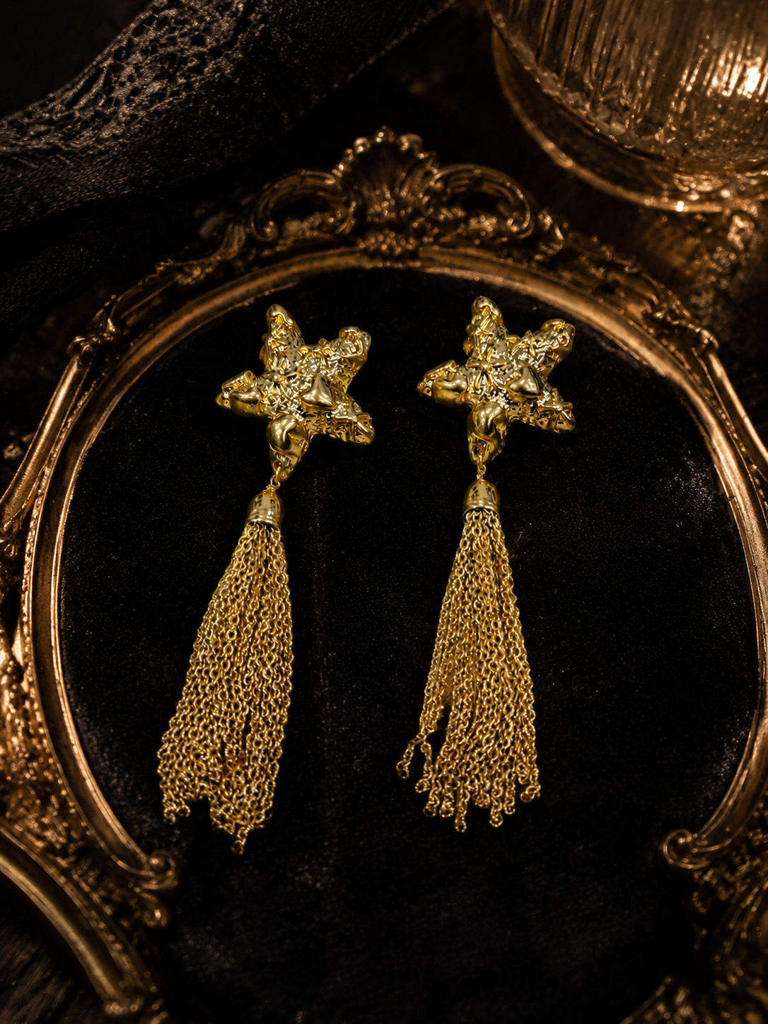 Close detail view of gold-tone star earrings with cascading chain tassels